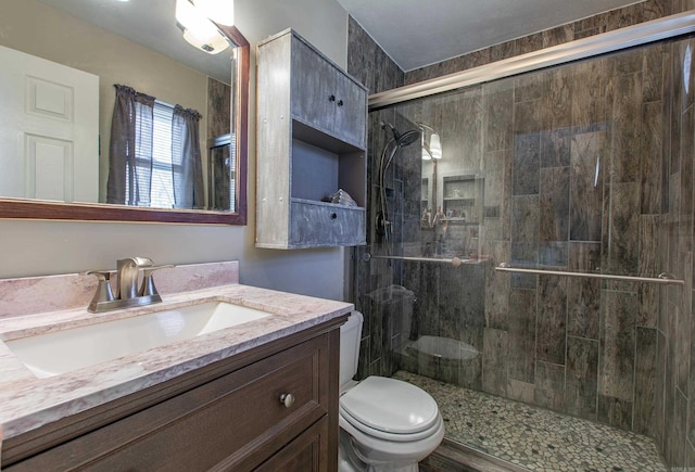 bathroom featuring a shower with door, toilet, and vanity