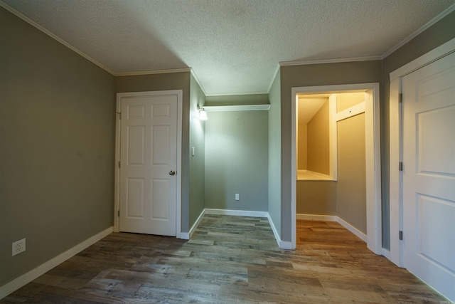 interior space featuring light wood-type flooring, ornamental molding, and a textured ceiling