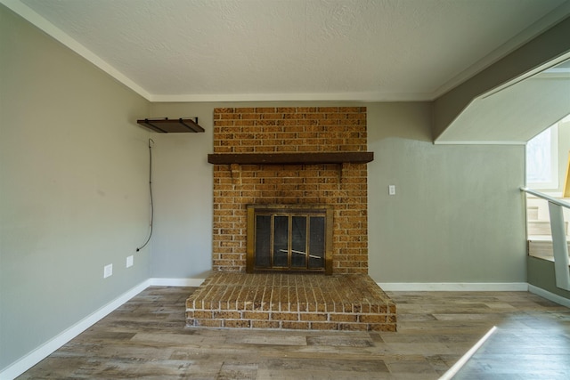 unfurnished living room featuring a textured ceiling, crown molding, a fireplace, and wood-type flooring