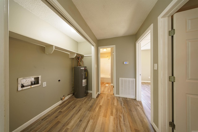 laundry room with a textured ceiling, water heater, light hardwood / wood-style floors, washer hookup, and hookup for an electric dryer