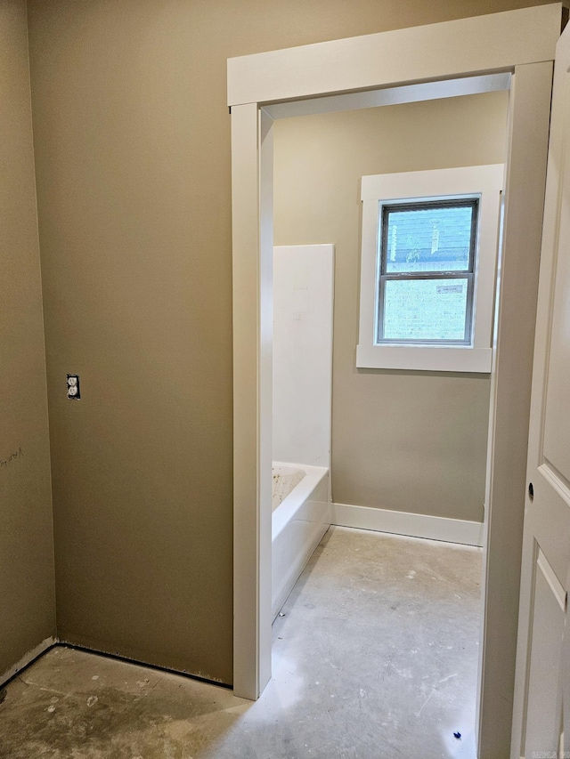 bathroom with a bath and concrete floors