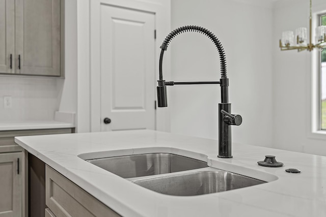 room details featuring a notable chandelier, light stone countertops, and sink