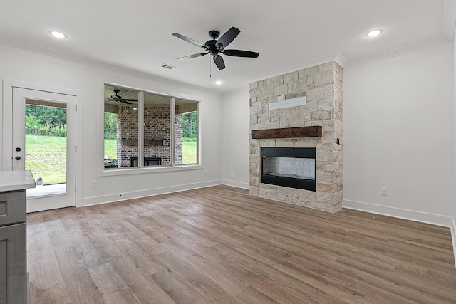 unfurnished living room with ceiling fan, crown molding, a fireplace, and light hardwood / wood-style flooring