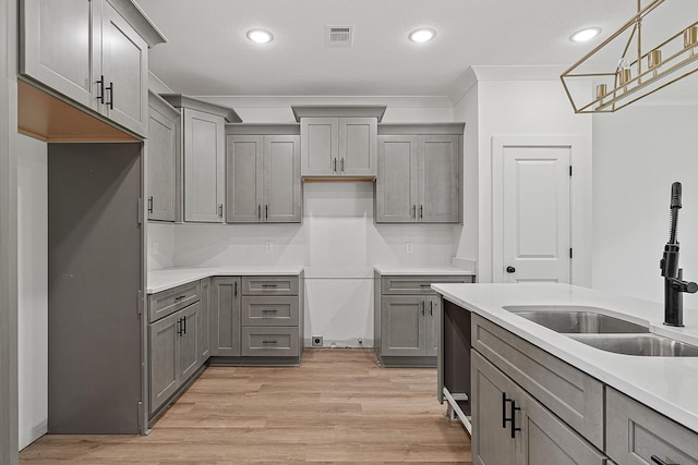 kitchen featuring pendant lighting, decorative backsplash, sink, light hardwood / wood-style flooring, and gray cabinetry