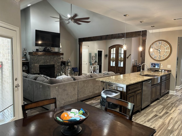 kitchen with dark brown cabinetry, pendant lighting, light hardwood / wood-style flooring, light stone counters, and sink