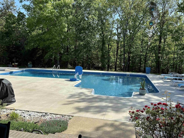 view of swimming pool featuring a diving board and a patio