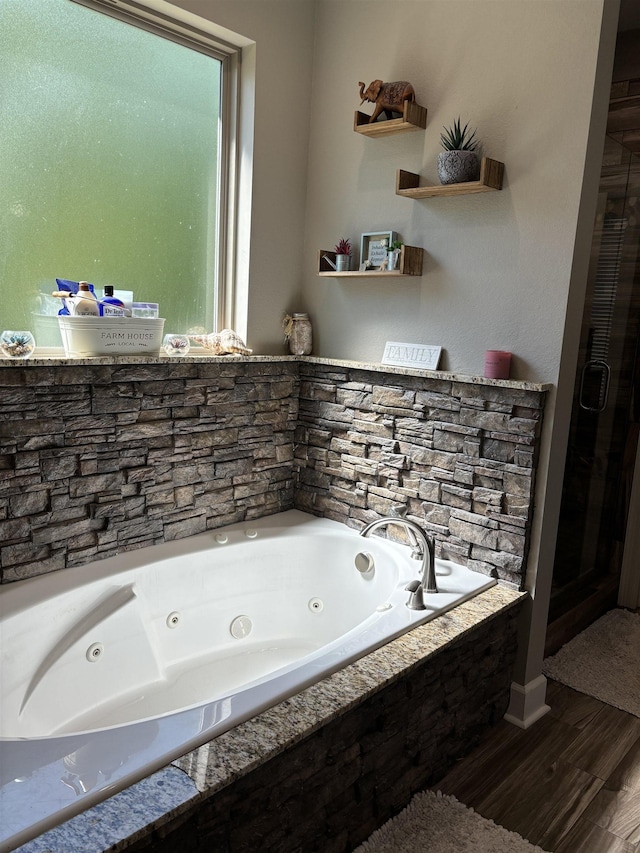 bathroom with wood-type flooring and tiled tub