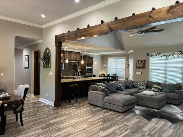 living room featuring ceiling fan, vaulted ceiling, ornamental molding, and wood-type flooring