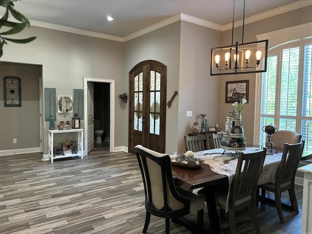 dining space with hardwood / wood-style floors, crown molding, and a chandelier
