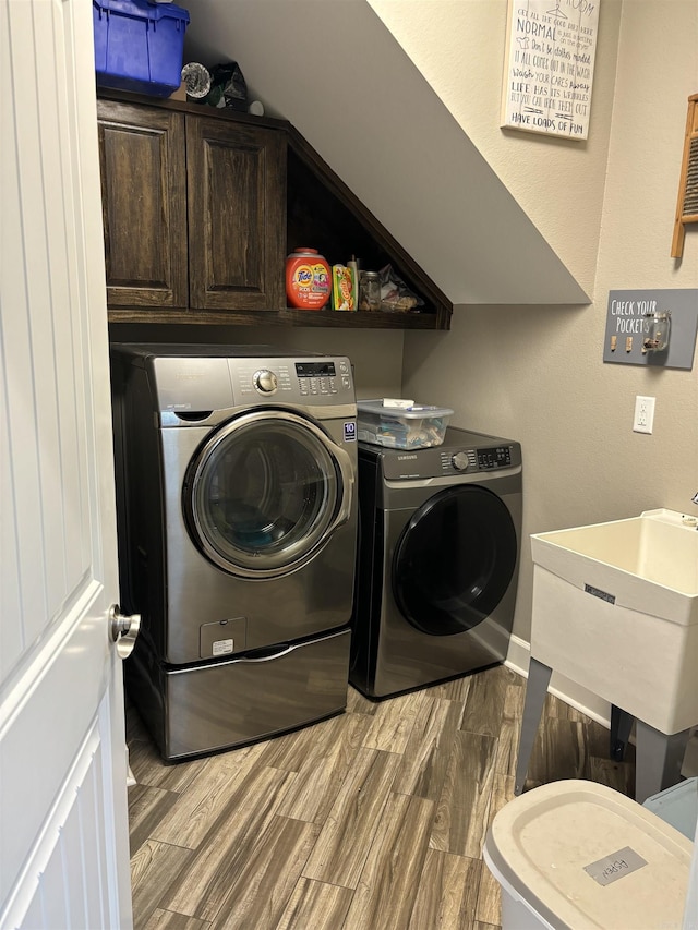 laundry room with cabinets, sink, separate washer and dryer, and hardwood / wood-style flooring