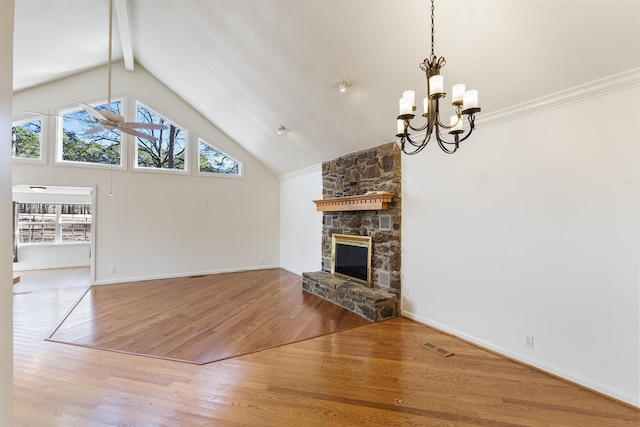 unfurnished living room with beamed ceiling, hardwood / wood-style flooring, a stone fireplace, ornamental molding, and a chandelier