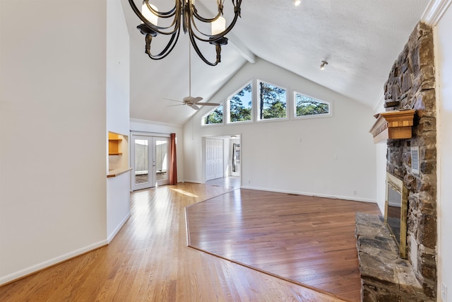 unfurnished living room with a fireplace, wood-type flooring, a textured ceiling, french doors, and ceiling fan with notable chandelier