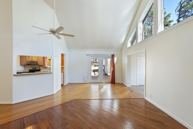 unfurnished living room featuring ceiling fan, a wealth of natural light, high vaulted ceiling, and light hardwood / wood-style flooring