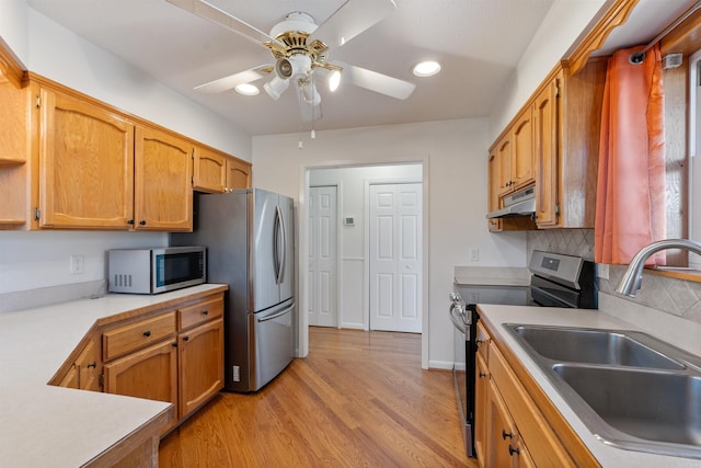 kitchen featuring ceiling fan, appliances with stainless steel finishes, tasteful backsplash, light wood-type flooring, and sink