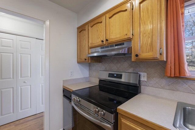 kitchen with light wood-type flooring, backsplash, electric range, and sink