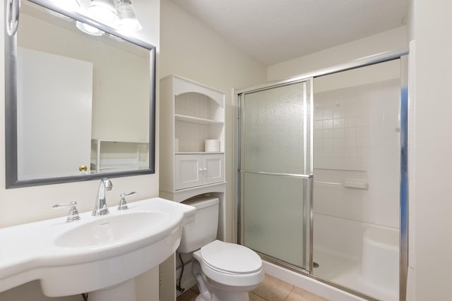 bathroom with sink, toilet, an enclosed shower, and tile patterned flooring