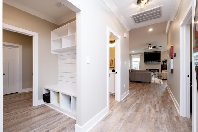 mudroom with light wood-type flooring, ceiling fan, crown molding, and a fireplace