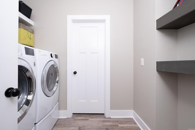 clothes washing area with separate washer and dryer and light hardwood / wood-style floors