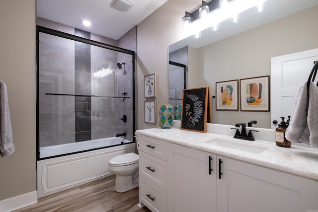 full bathroom featuring hardwood / wood-style floors, toilet, vanity, and shower / bath combination with glass door