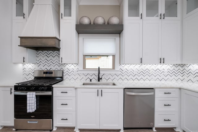 kitchen featuring appliances with stainless steel finishes, custom exhaust hood, white cabinetry, sink, and backsplash