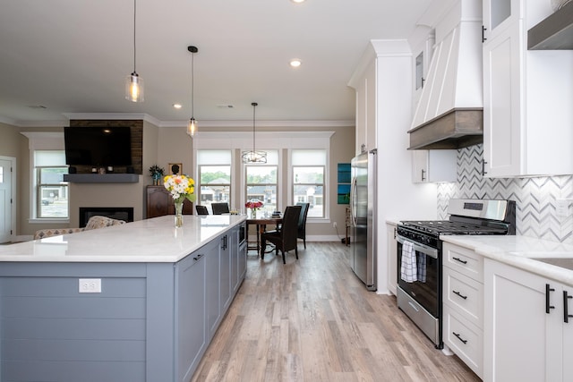 kitchen with custom exhaust hood, white cabinets, and appliances with stainless steel finishes