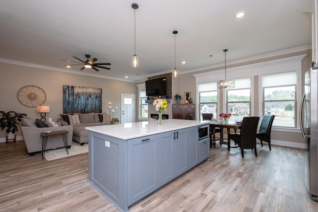 kitchen featuring decorative light fixtures, light wood-type flooring, stainless steel appliances, and a kitchen island