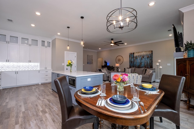 dining area featuring ceiling fan with notable chandelier, light hardwood / wood-style flooring, and crown molding