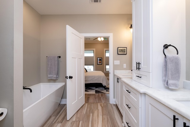 bathroom featuring ceiling fan, hardwood / wood-style floors, vanity, and a bathing tub