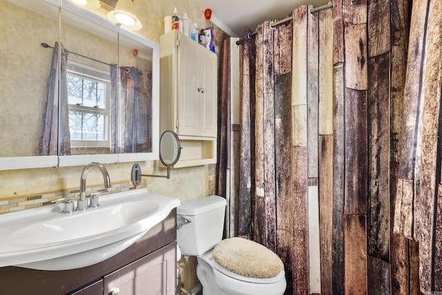 bathroom featuring toilet, vanity, and backsplash