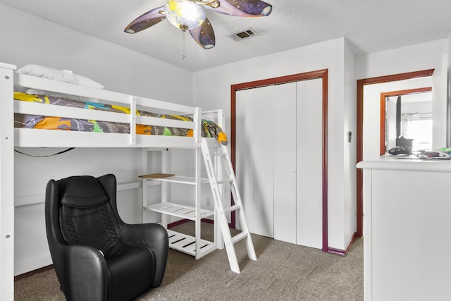 bedroom with ceiling fan, a closet, dark carpet, and a textured ceiling