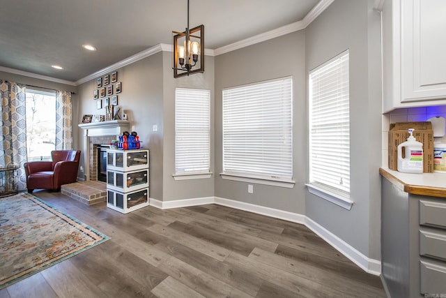 dining space with a chandelier, crown molding, a fireplace, and hardwood / wood-style floors