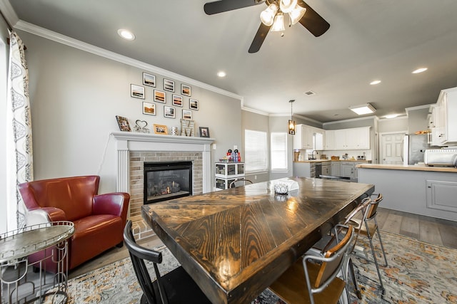 dining area with a fireplace, sink, ornamental molding, and hardwood / wood-style flooring