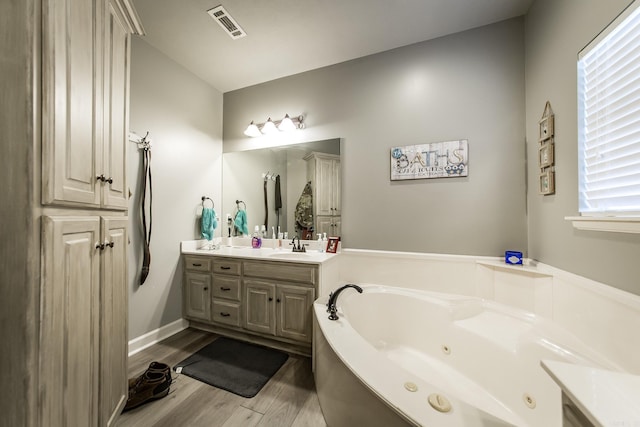 bathroom featuring wood-type flooring, vanity, a wealth of natural light, and a bath