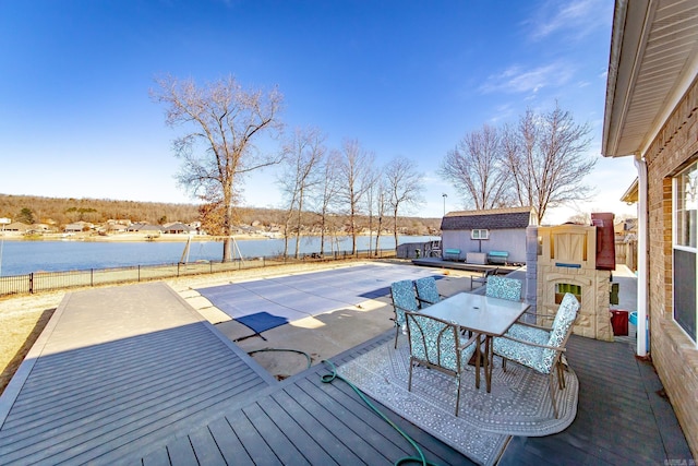 deck with a patio area, an outdoor fireplace, a water view, and a shed