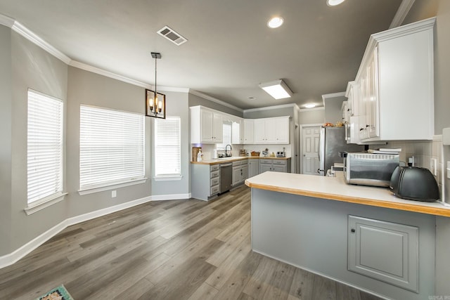 kitchen with kitchen peninsula, stainless steel appliances, pendant lighting, white cabinets, and sink