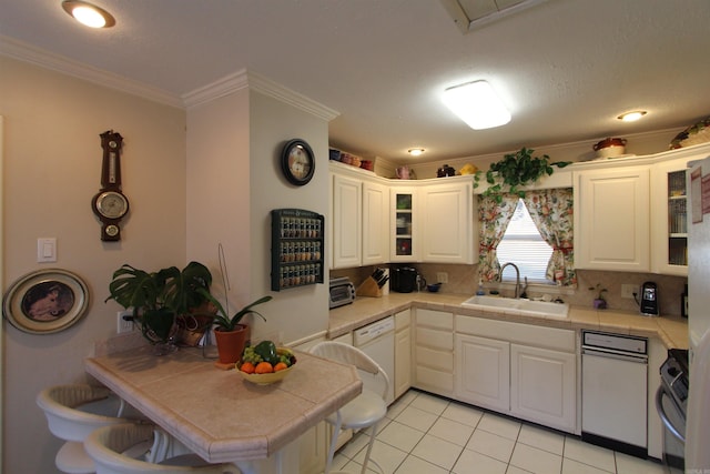 kitchen with tile countertops, sink, light tile patterned flooring, ornamental molding, and white cabinets