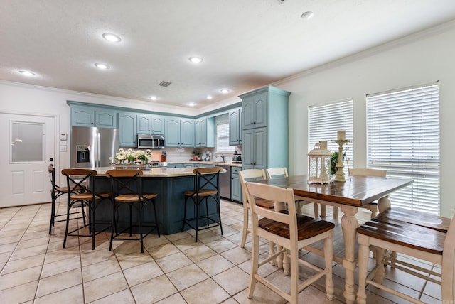 kitchen with a center island, stainless steel appliances, tasteful backsplash, ornamental molding, and light tile patterned floors