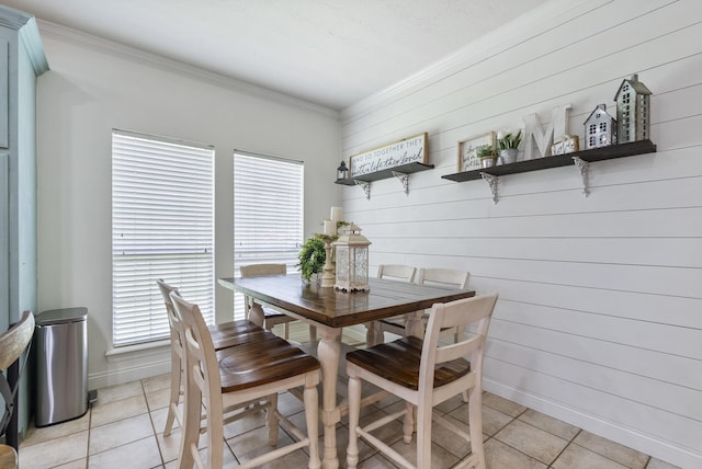 dining area with wood walls, light tile patterned floors, and ornamental molding