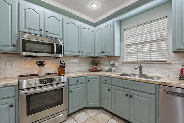 kitchen with backsplash, sink, appliances with stainless steel finishes, a textured ceiling, and light tile patterned floors