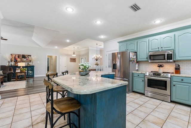 kitchen featuring light tile patterned floors, appliances with stainless steel finishes, a kitchen island, and pendant lighting