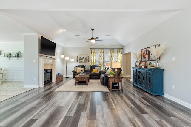 living room featuring ceiling fan, vaulted ceiling, dark wood-type flooring, and wooden walls