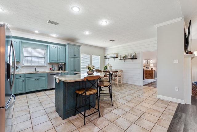 kitchen with stainless steel appliances, a kitchen island, blue cabinetry, a wealth of natural light, and sink