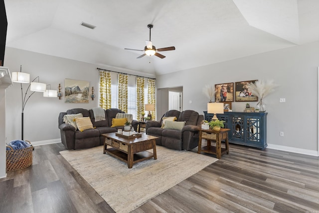 living room featuring ceiling fan, vaulted ceiling, dark wood-type flooring, and a tray ceiling