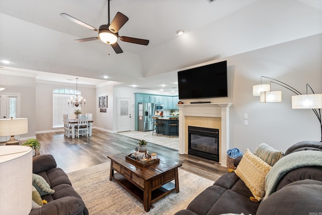 living room featuring light wood-type flooring, ceiling fan, crown molding, and a raised ceiling