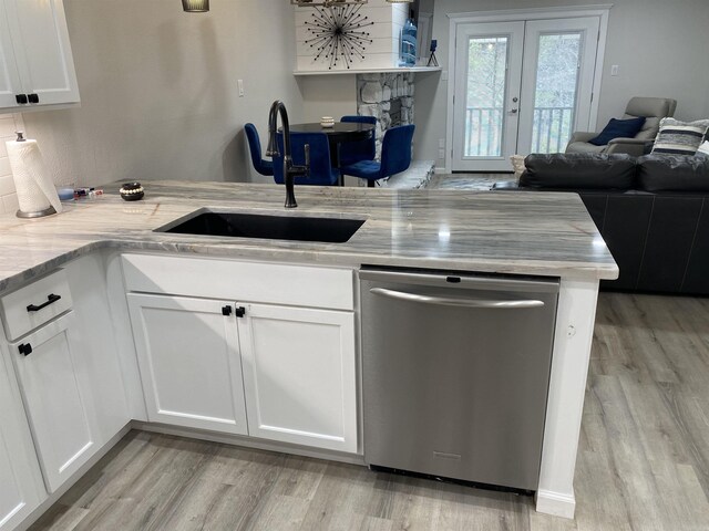 kitchen with stainless steel dishwasher, sink, light hardwood / wood-style flooring, white cabinets, and light stone counters