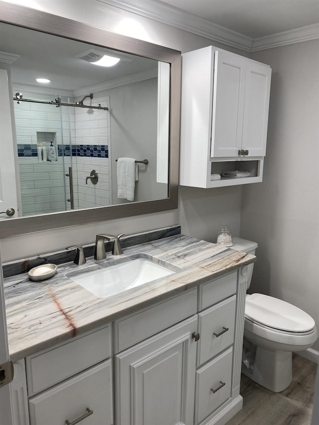 bathroom with hardwood / wood-style floors, vanity, toilet, walk in shower, and ornamental molding