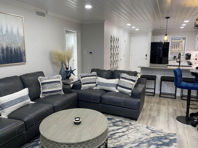 living room featuring light wood-type flooring, wood ceiling, sink, and ornamental molding
