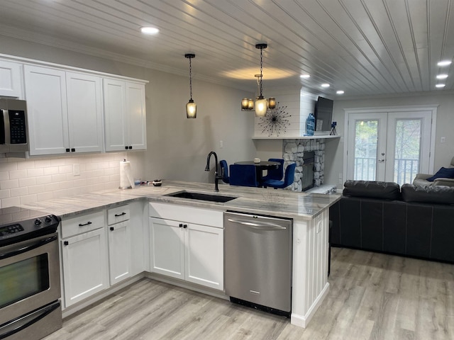 kitchen with white cabinetry, kitchen peninsula, stainless steel appliances, hanging light fixtures, and sink