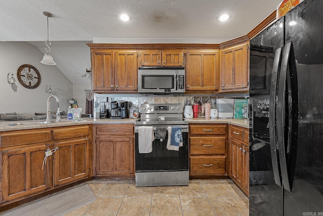 kitchen with light tile patterned floors, appliances with stainless steel finishes, backsplash, pendant lighting, and sink