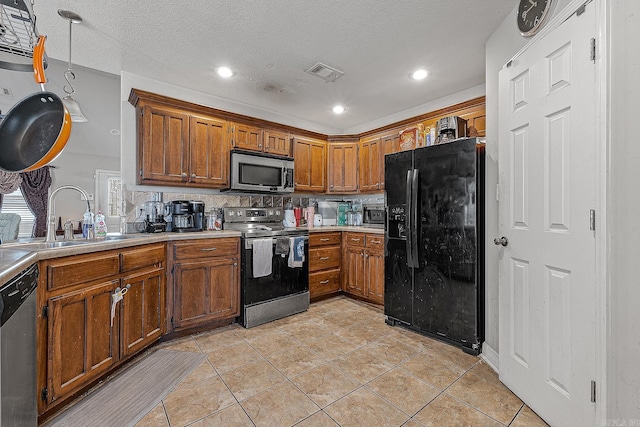 kitchen featuring a textured ceiling, appliances with stainless steel finishes, sink, backsplash, and light tile patterned floors